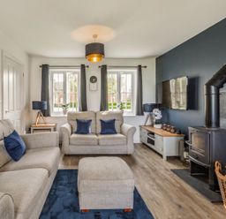 A living room with sofas and a wood stove next to a TV at Lantern House in Filey