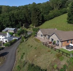 A rural property with multiple buildings surrounded by trees and grassy hills at Pen Y Banc in Llanfaredd near Builth Wells