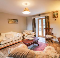 A living room with sofas a wooden rocking chair a coffee table and French doors at Coffey's in Ballymacarbry County Waterford