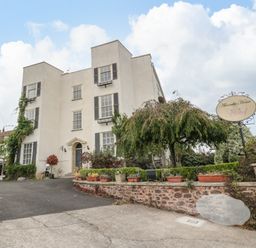 An exterior view of a multi-story building with plants and a driveway at Alcombe House in Minehead