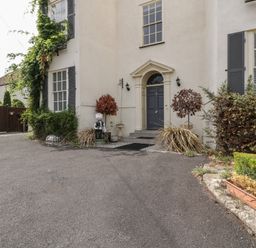 Front entrance of a house with a grey door plants and shrubs on either side at Alcombe House in Minehead