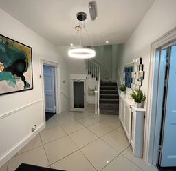 A hallway with stairs a circular ceiling light and plants on a radiator cover at Alcombe House in Minehead
