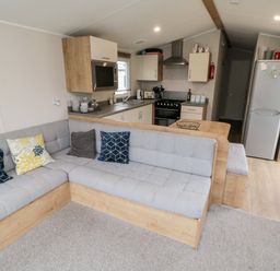 A kitchen and living area with an L-shaped sofa and cushions at Pines 30 in Cayton