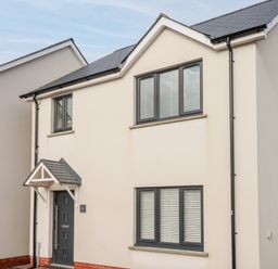 A two-story house with a gray front door and windows at LunaRoxx 6 Meadow Gardens Kilgetty