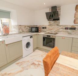 A kitchen with a washing machine oven microwave and a sink at Donni Hall Cottage in Beadnell