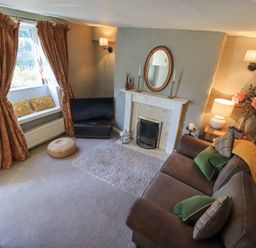 A living room with a sofa cushions and a fireplace at Lavender Cottage in Cark In Cartmel