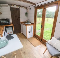 A small kitchen area with wooden countertops a sink a toaster and an oven next to double glass doors with a view of a grassy yard at Fern in Broad Langdon near Wainhouse Corner