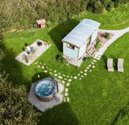 A small cabin with path leading to a hot tub two lounge chairs and a seating area outdoors at Fern Broad Langdon near Wainhouse Corner
