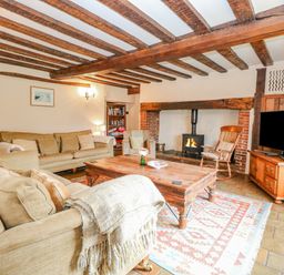 A living room with sofas a wooden coffee table a fireplace and a television at Manor Farm House in Bacton