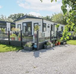 A mobile home with a deck and plants at Lilac Lodge in Carnforth