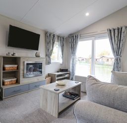 A living room with a mounted television fireplace coffee table and sliding glass doors at Fountain View in Warton near Carnforth