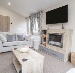 A living room with a sofa coffee table fireplace and television at Fountain View in Warton near Carnforth