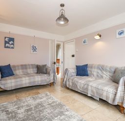 A living room with two sofas covered with plaid fabric and cushions at Beck View in Sheringham