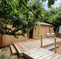 A wooden cabin with a deck and outdoor seating at Brambly Cabin in Crediton