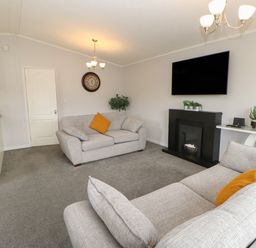 A living room with two sofas a wall-mounted TV a fireplace and a table with plants at Mildred's Lodge in Felton