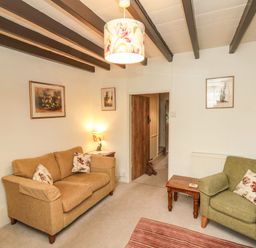A living room with a brown sofa and green armchair and wooden beams on the ceiling at 12 Castlegate in Pickering