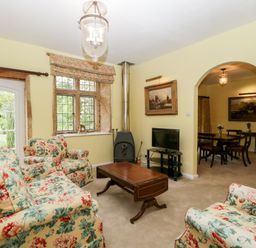 A living room with floral sofas wooden coffee table and a television next to a window at Ham cottage East Lambrook near South Petherton