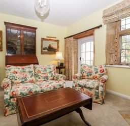 A sitting room with floral upholstered armchairs and a wooden coffee table at Ham cottage in East Lambrook near South Petherton