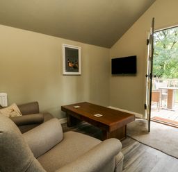 A living room with a sofa armchair coffee table TV and an open door leading to a balcony at Pheasant in Bedale