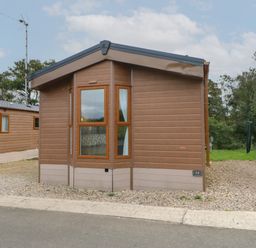 A small brown wooden cabin with multiple windows and gravel surrounding at Bock Retreat in Felton