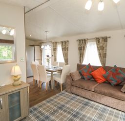 A living room and dining area with a sofa, dining table with chairs, and a cabinet with a lamp at Bock Retreat in Felton