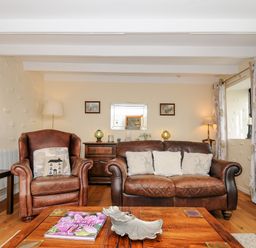 A living room with leather armchair and sofa wooden coffee table and side tables at Church View Cottage Near Looe