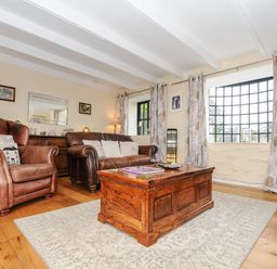 A living room with leather armchairs sofa wooden coffee table large window and television at Church View Cottage Near Looe