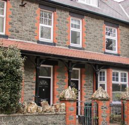 Stone brick terraced houses with black doors and windows behind a low stone wall and gate at Gwyder in Penmaenmawr
