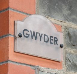A sign with the word Gwyder mounted on a brick and stone wall at Gwyder in Penmaenmawr