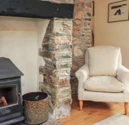 A living room with a fireplace and an armchair at Wayside near Kingsbridge