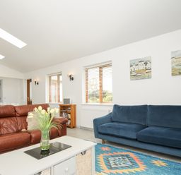 A living room with two sofas a coffee table with flowers a rug and paintings on the wall at Lambley View in Bude