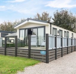 An exterior view of a mobile home with a deck and outdoor furniture at 3 Yealands in Carnforth