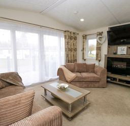 A living room with two brown sofas a coffee table a mounted TV and fireplace at 3 Yealands in Carnforth