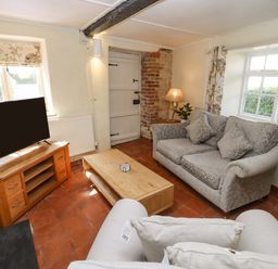 A living room with a sofa armchair wooden coffee table and television on a wooden stand at 5 Packhorse in Purton
