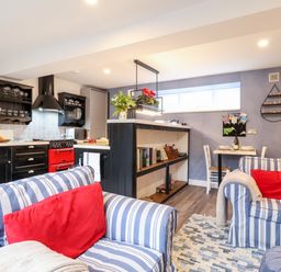 A kitchen and living room with striped sofas and red cushions at Tower End Cottage in Melton