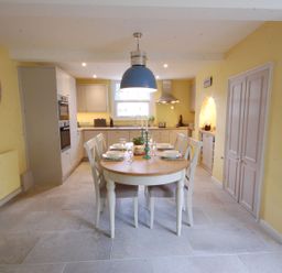 A kitchen with a dining table set for six under a blue pendant light at Crabbe Corner in Aldeburgh