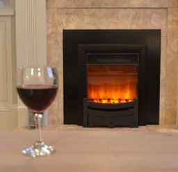 A glass of red wine on a table in front of a fireplace at Crabbe Corner in Aldeburgh