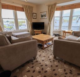 A living room with two sofas a wooden coffee table a television and large windows at Peak View in Keswick