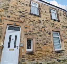 The exterior of a stone building with white doors and windows at Bonnies Retreat in Amble