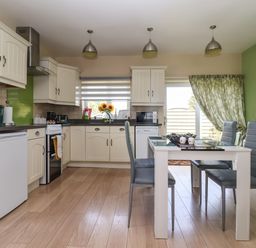 A kitchen with white cabinets a dining table with four chairs and green walls at Church View in Atwick