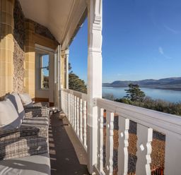 A balcony with chairs overlooking water and mountains at Bryn Mel Manor Straits View Menai Bridge