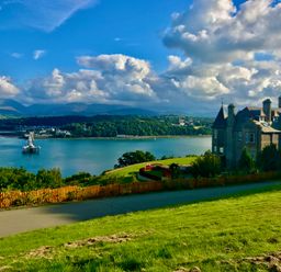 A large building on a hill overlooking water and distant mountains at Bryn Mel Manor Straits View Menai Bridge