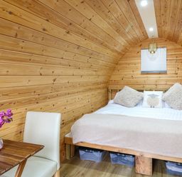 A bedroom with a wooden bed and a small table with a flower vase at The Pod at Bank House Farm The Blythe near Hixon