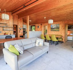 A living room with two gray sofas green chairs wooden walls and ceiling at Greengarth in Yanwath near Penrith