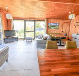 A living room with a sofa ottoman TV chairs tables and wooden walls at Greengarth in Yanwath near Penrith