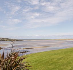 A coastal landscape with grassy hills overlooking a sandy tidal estuary at Upper Killult in Killult near Gortahork County Donegal