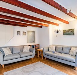 A living room with two grey sofas and wooden beams on the ceiling at Honey Cottage in Port Isaac