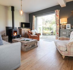 A living room with sofas a wood burning stove and a wooden coffee table at The Croft in Newport Pembrokeshire