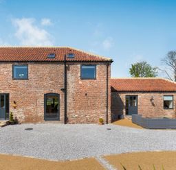 A brick house with three doors and three windows along with an outdoor seating area at Partridge Place in Burton Pidsea