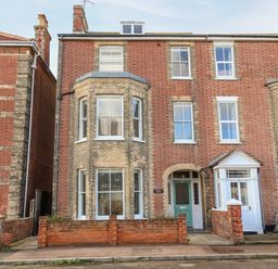A brick residential building with multiple windows and a green front door at Collett House in Southwold